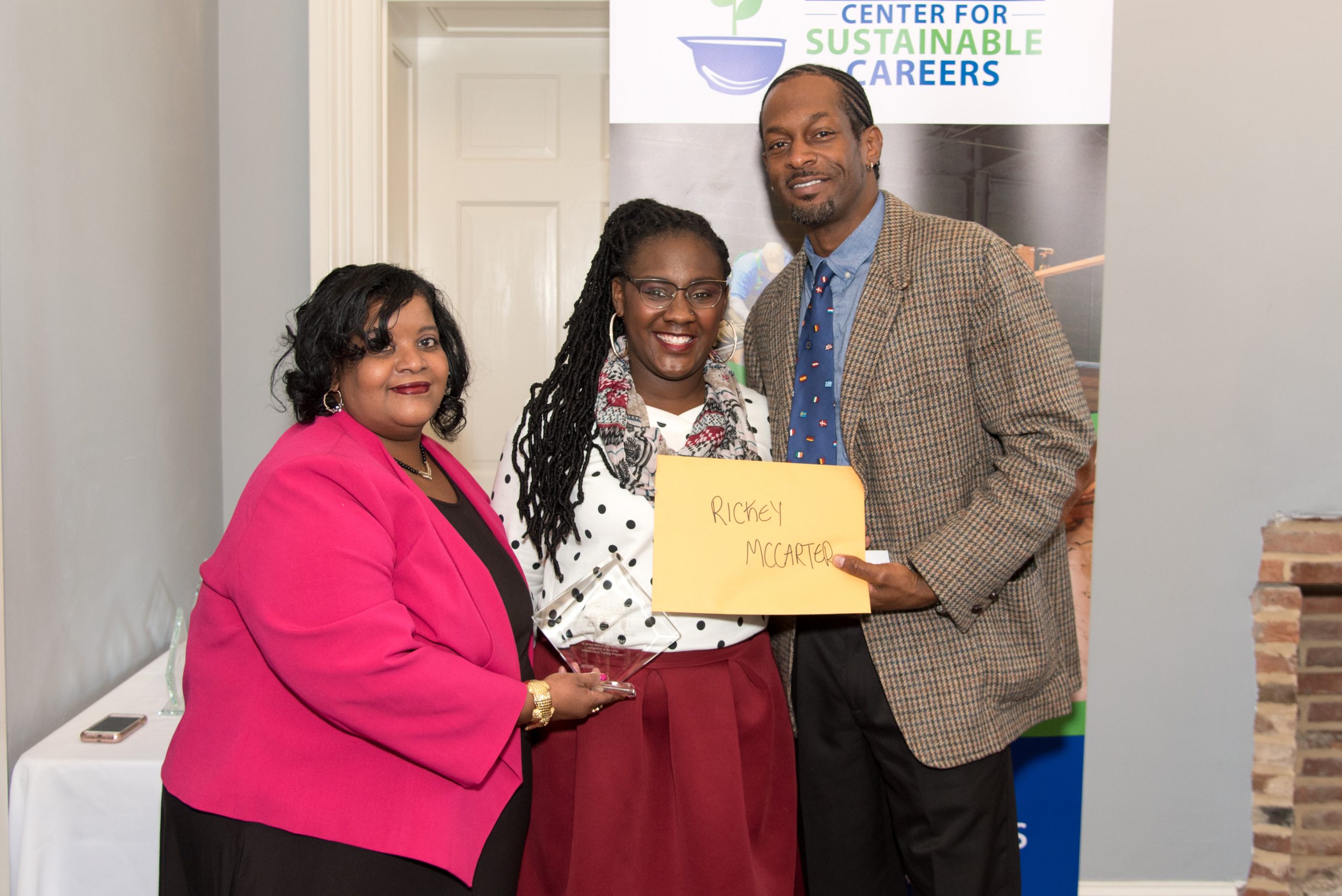 Civic Works staff members Kimberly Armstrong and Vanessa Galloway congratulate Rickey McCarter after graduating from the Workforce Collaborative.