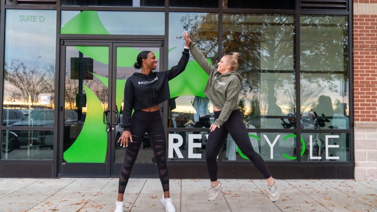 Two women high fiving outside a fitness studio