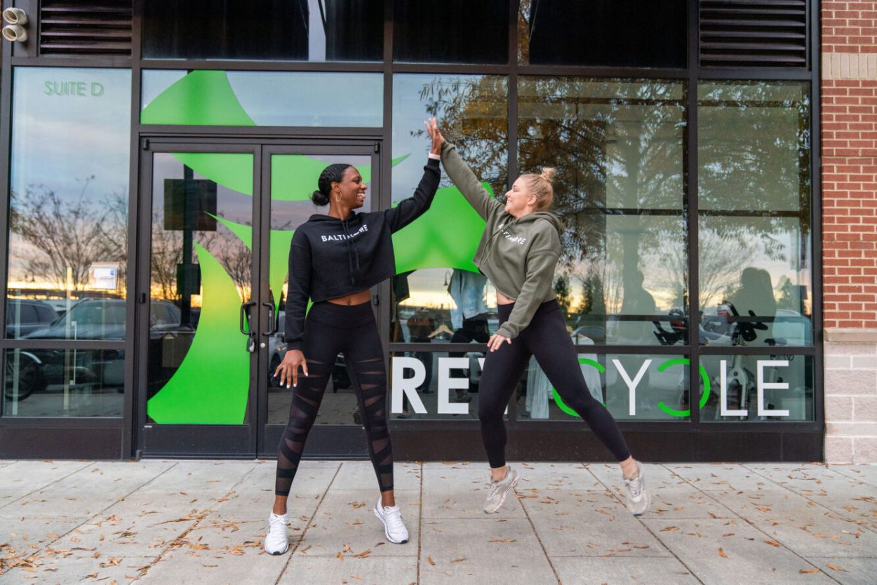 Two women high fiving outside a fitness studio