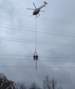 Linewoker on standing on the side of a helicopter
