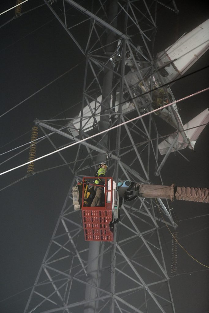 Lineworkers ascend the tower to secure the plane